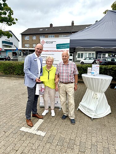 Ehepaar Schmitz Arzt mit einem älteren Ehepaar auf einem Marktstand